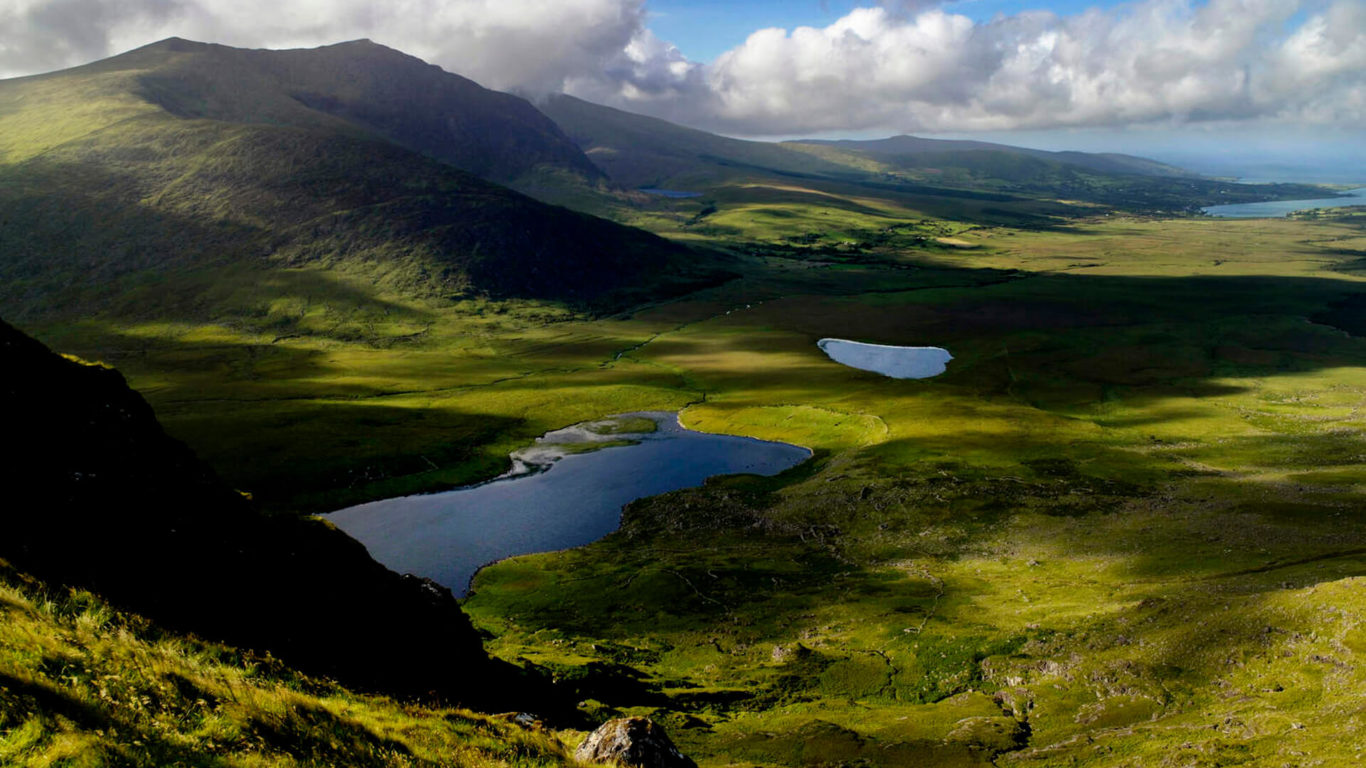 Stunning view of lush Irish landscape with rolling hills and reflective lakes under a cloudy sky, perfect for nature lovers.