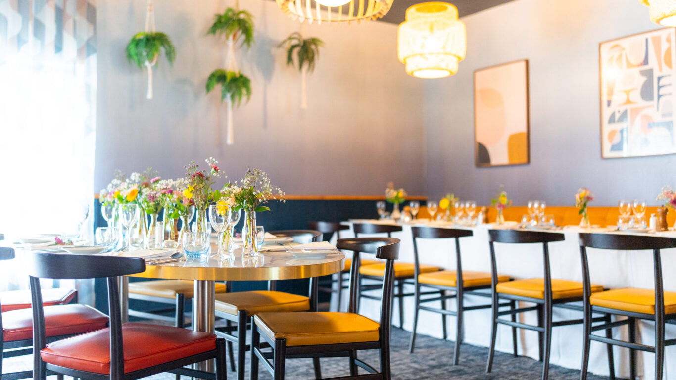 Elegant hotel dining room with modern decor, fresh flowers on tables, stylish lighting, and comfortable seating for a memorable meal.