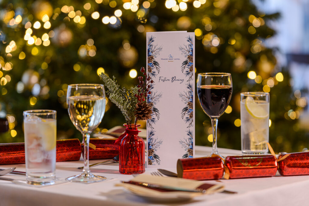 Festive Hotel Dining Experience Elegant festive dining table set with menu, wine, and Christmas décor at a luxury hotel in a warm, inviting atmosphere.
