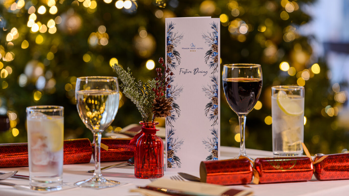 Elegant festive dining table set with menu, wine, and Christmas décor at a luxury hotel in a warm, inviting atmosphere.