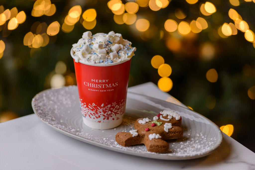 Cosy Holiday Drink Delight Festive Christmas hot cocoa with marshmallows and gingerbread on a plate, surrounded by warm holiday lights.