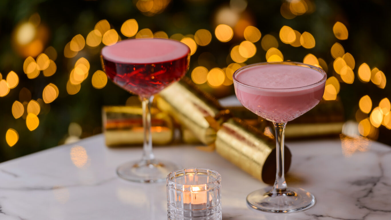 Festive cocktails with glowing bokeh lights on a marble table, offering a luxurious hotel bar experience.